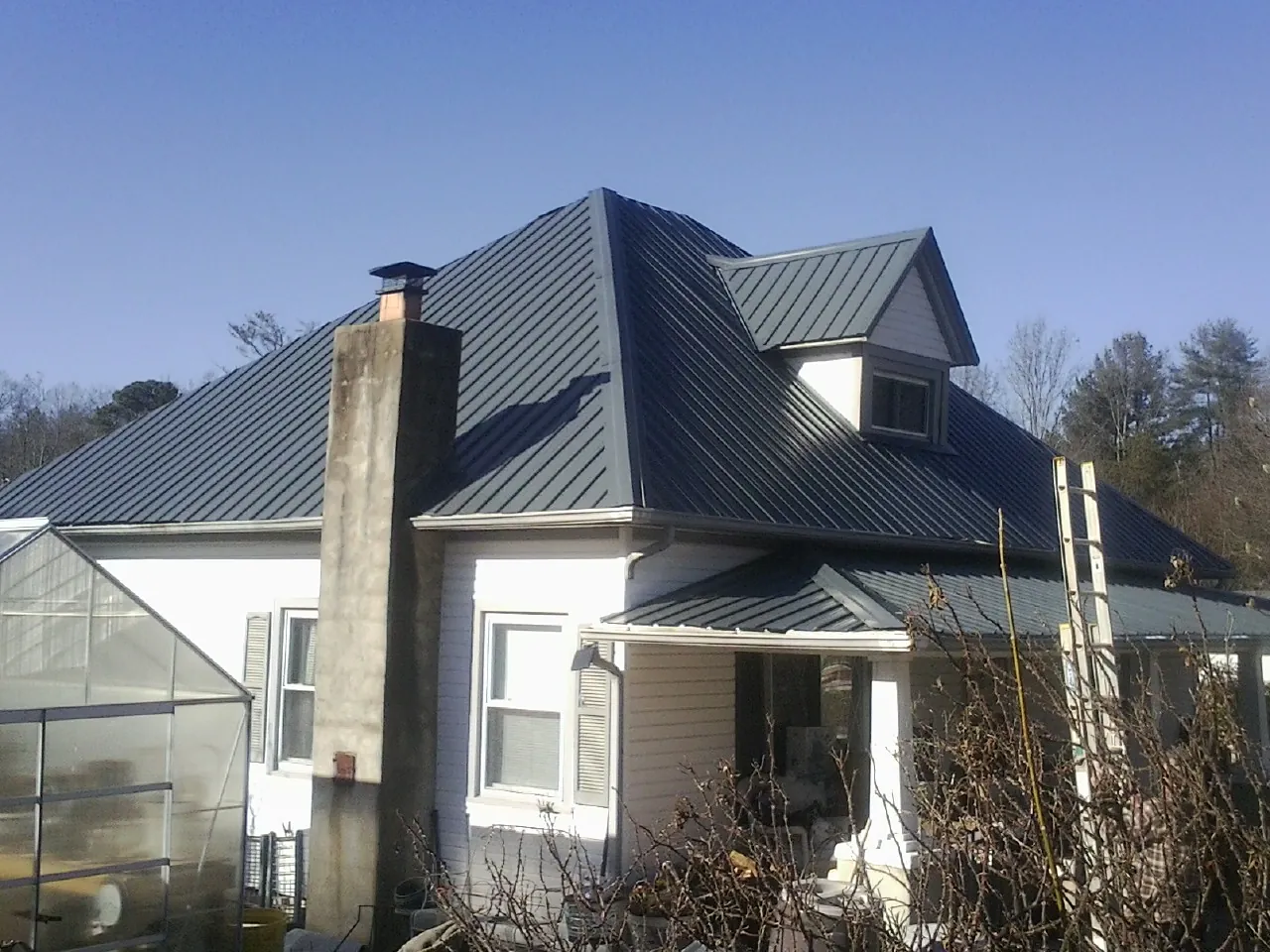 Dark blue standing seam metal roof on a white farmhouse with dormer — Slate & Tile Roof Repair by Roofing Brothers in Fortville