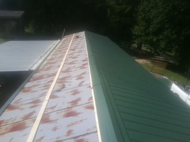 Old rusted panels beside newly installed green metal roofing — Wind Damage Roof Repair by Roofing Brothers in Fortville
