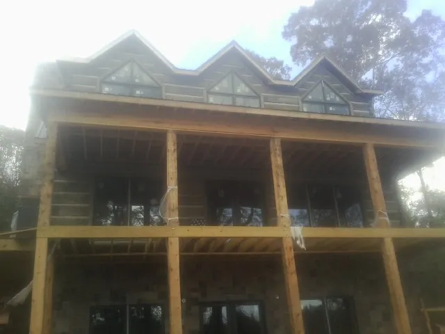 Dormers and porch framing on a large log home under construction — Roof Coating work by our crew in Fortville