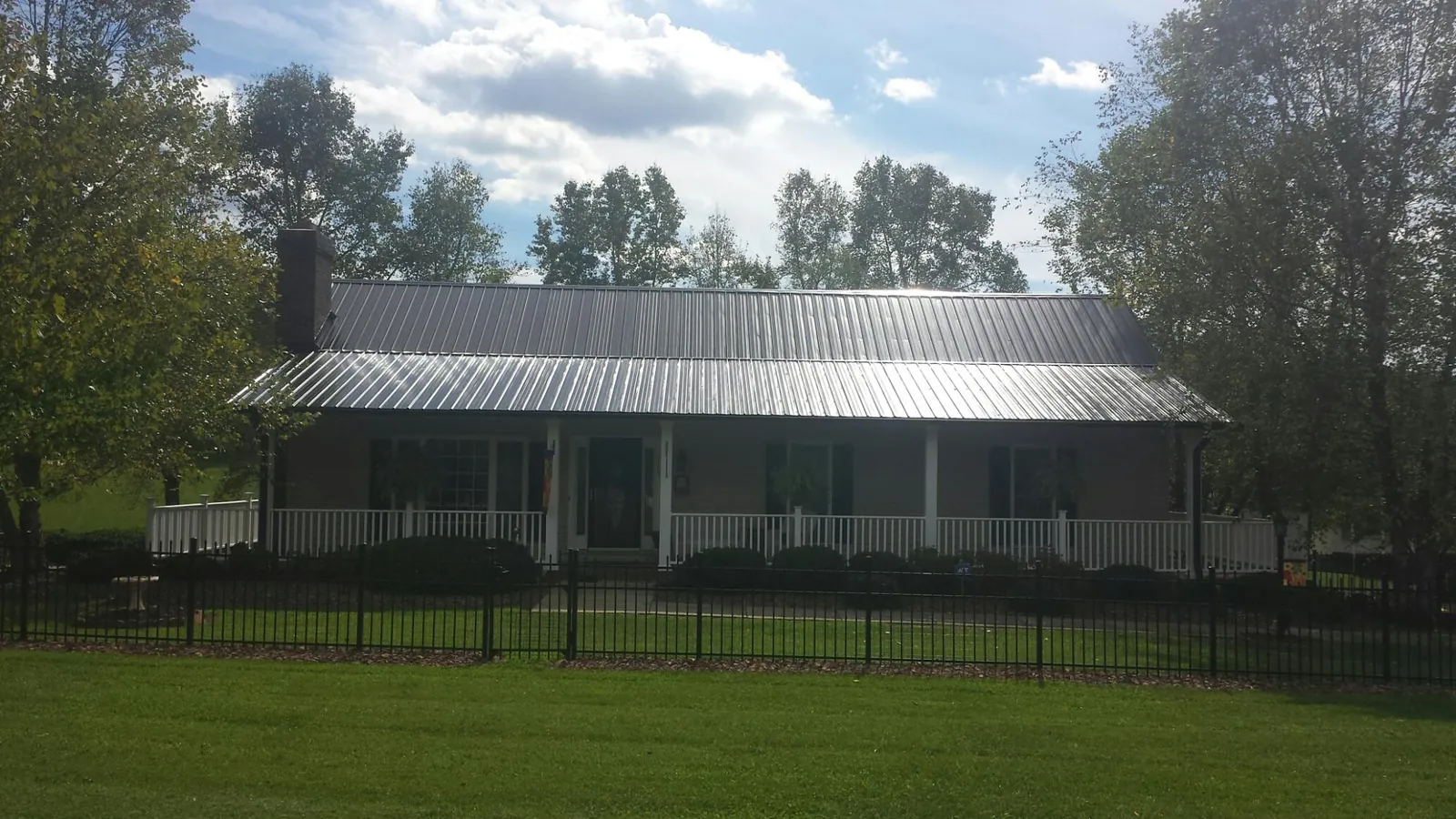 Gray metal roof on a brick ranch with a full width front porch — Gutter Guard Installation work by our crew in Fortville
