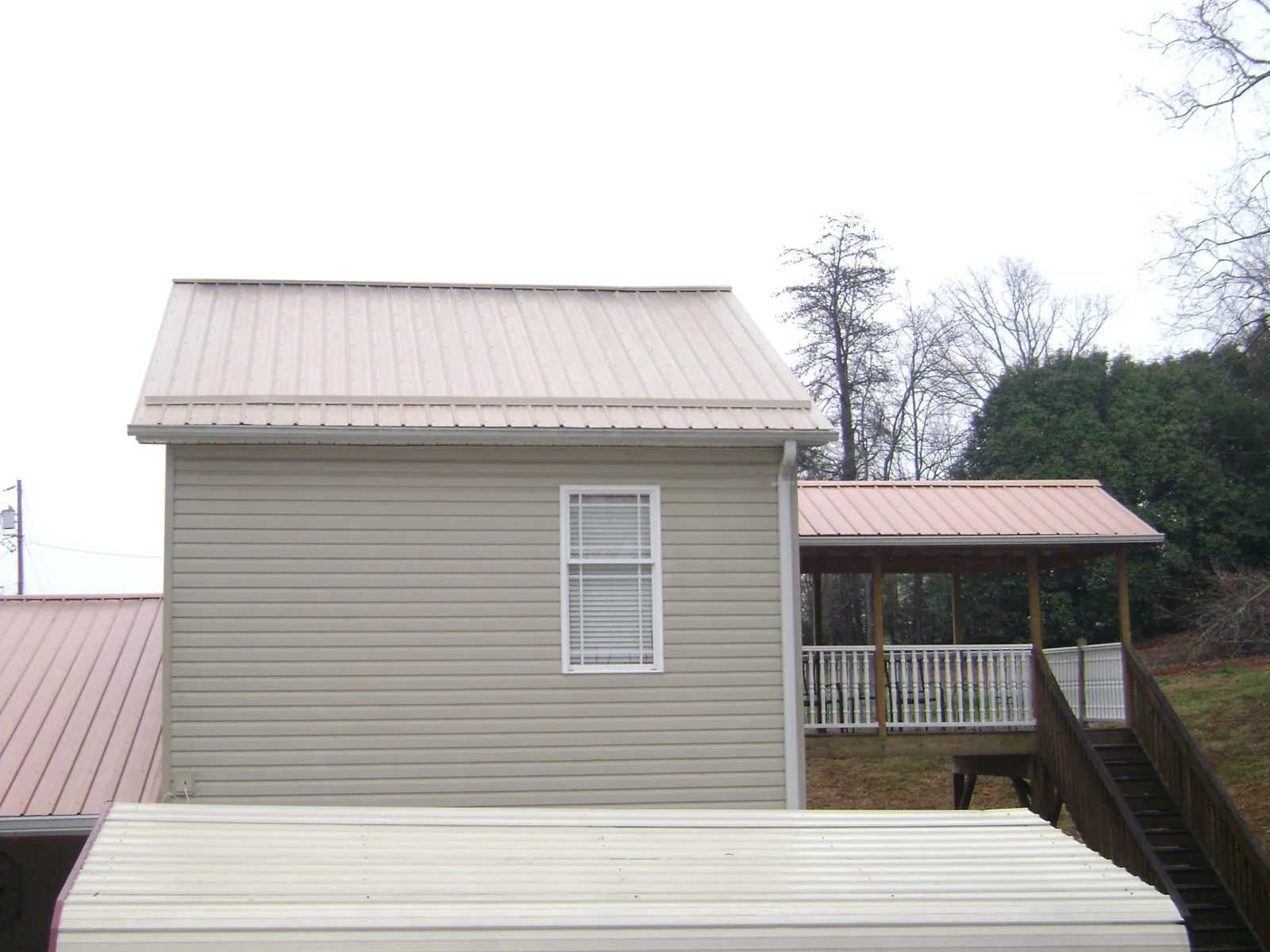 Tan metal roofs on a two story addition and attached porch, from a Roof Replacement job in Fortville