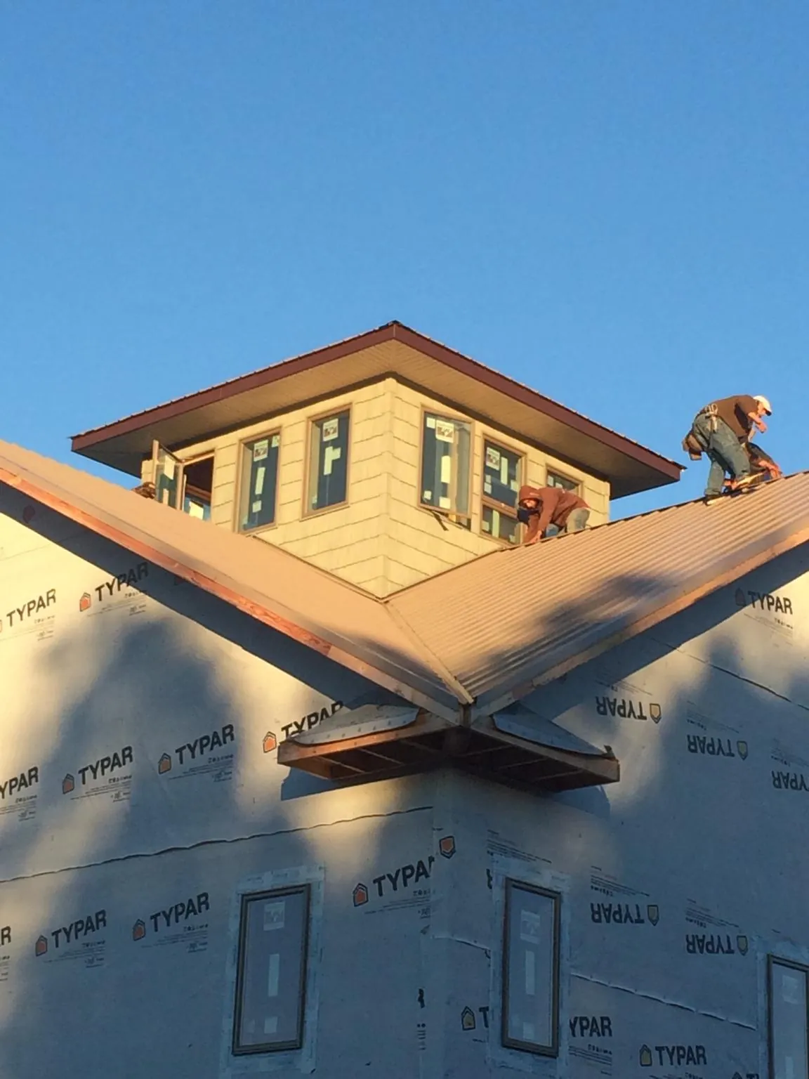 Roofers working around a rooftop cupola on a new metal roof at sunset — Roof Waterproofing in Fortville by Roofing Brothers